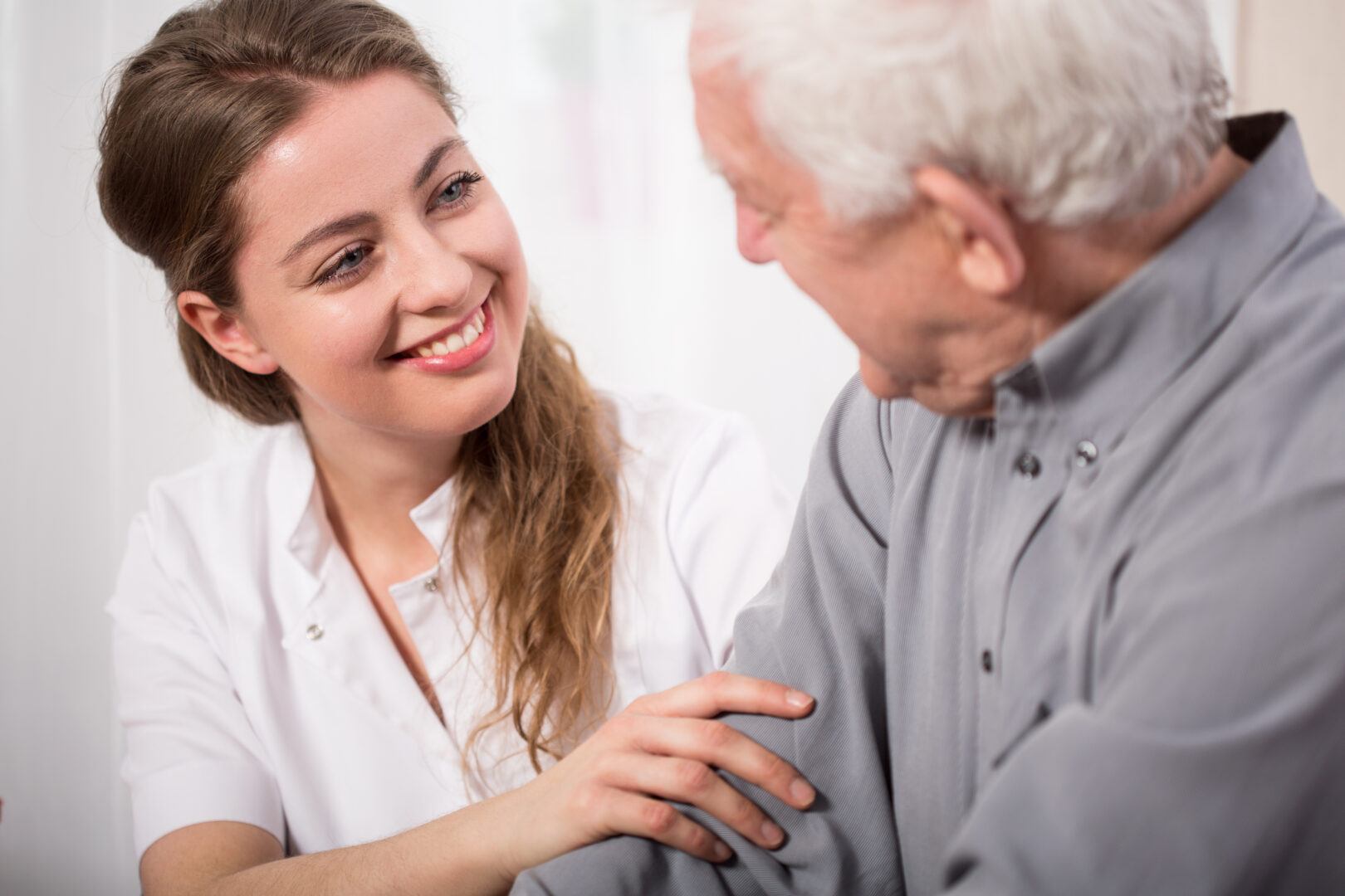 a smiling carer smiles at an elderly patient