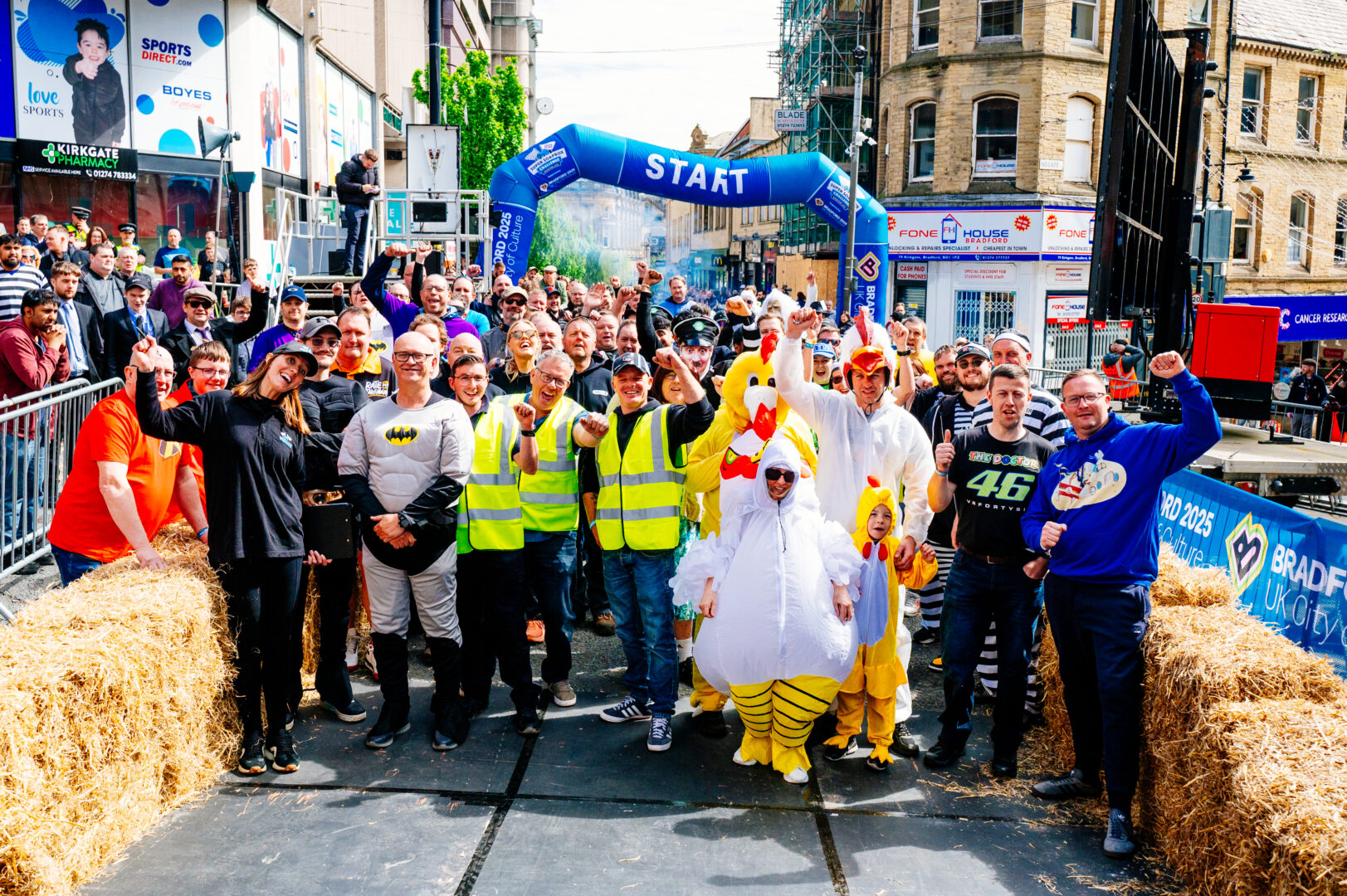 a group of competitors stand together, some in costume, as the start of the soapbox race course