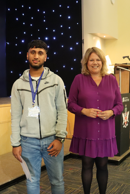 a student stands with an award and a certificate