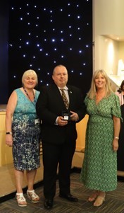 a member of staff stands holding an award with two other members of staff