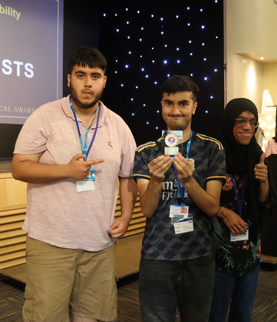 two students stand together holding awards and smiling