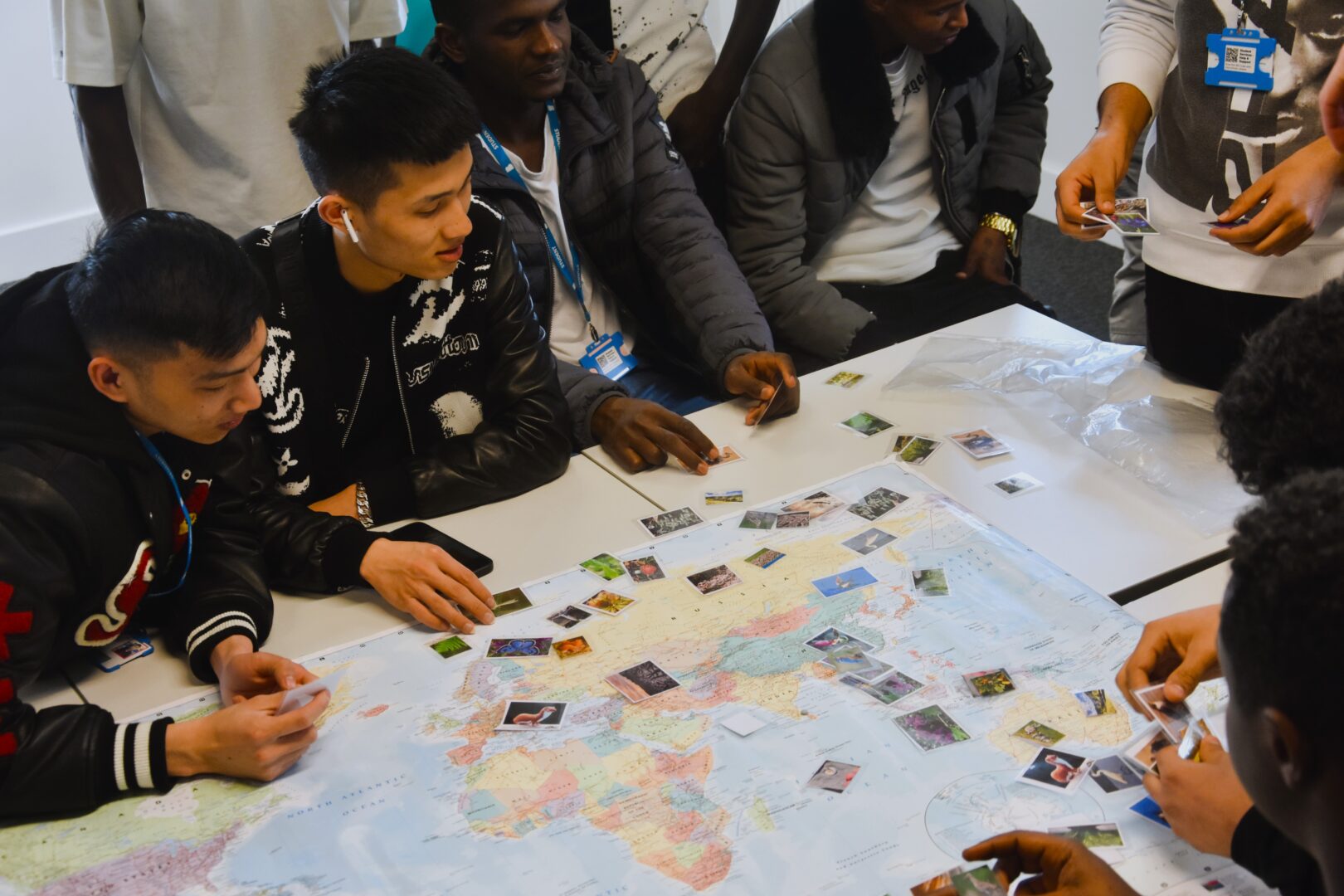 a group of students sit together placing pictures onto a map