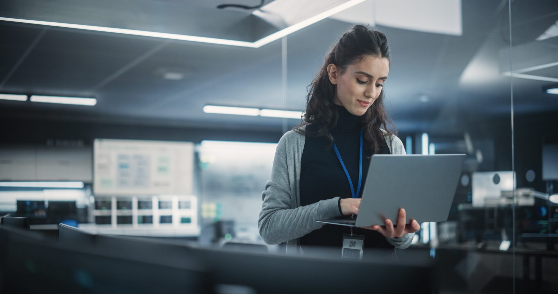 a woman stands with a laptop in her hands