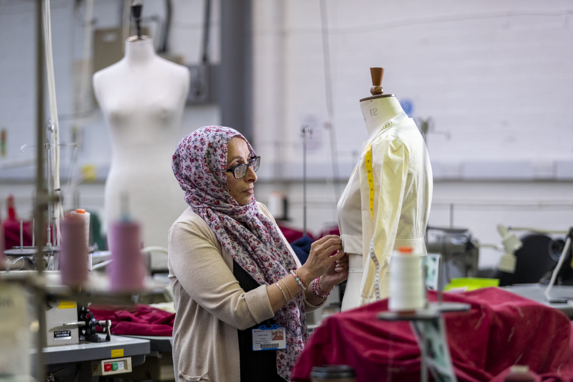 a fashion student stands in the foreground fitting clothing to a mannequin model