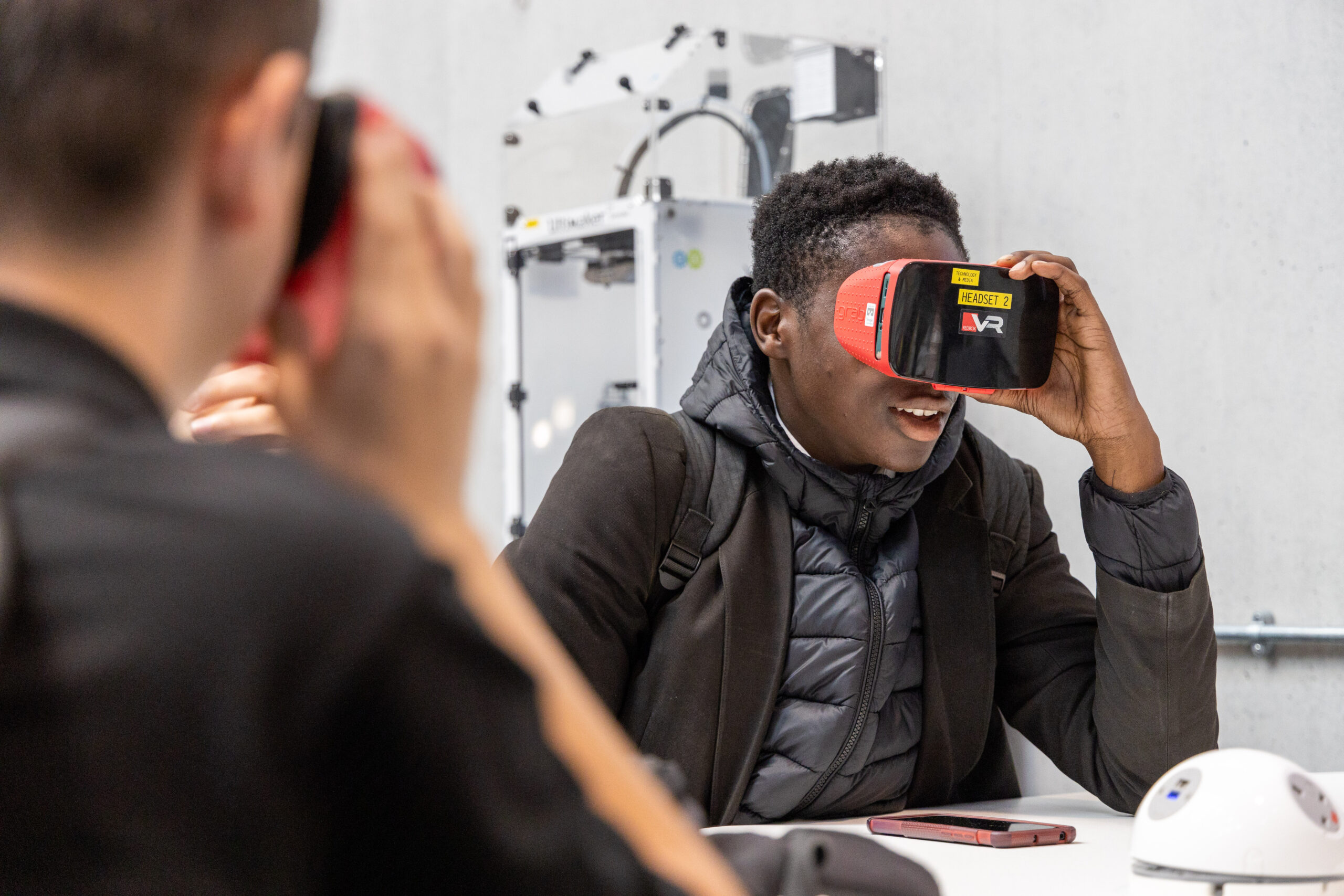 a young black male student sits wearing a virtual reality headset