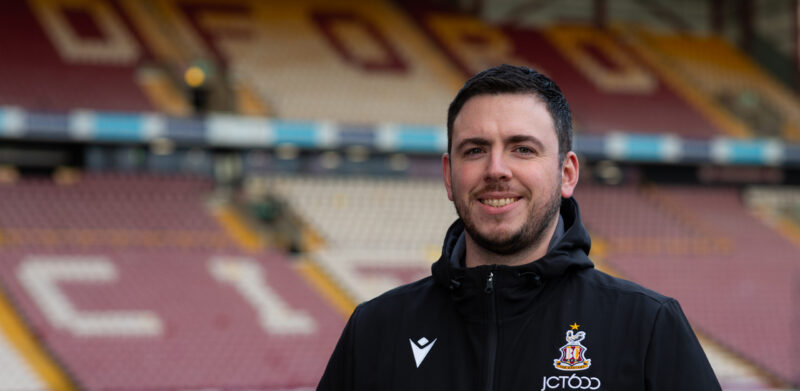 A man smiling at the camera at a football stadium