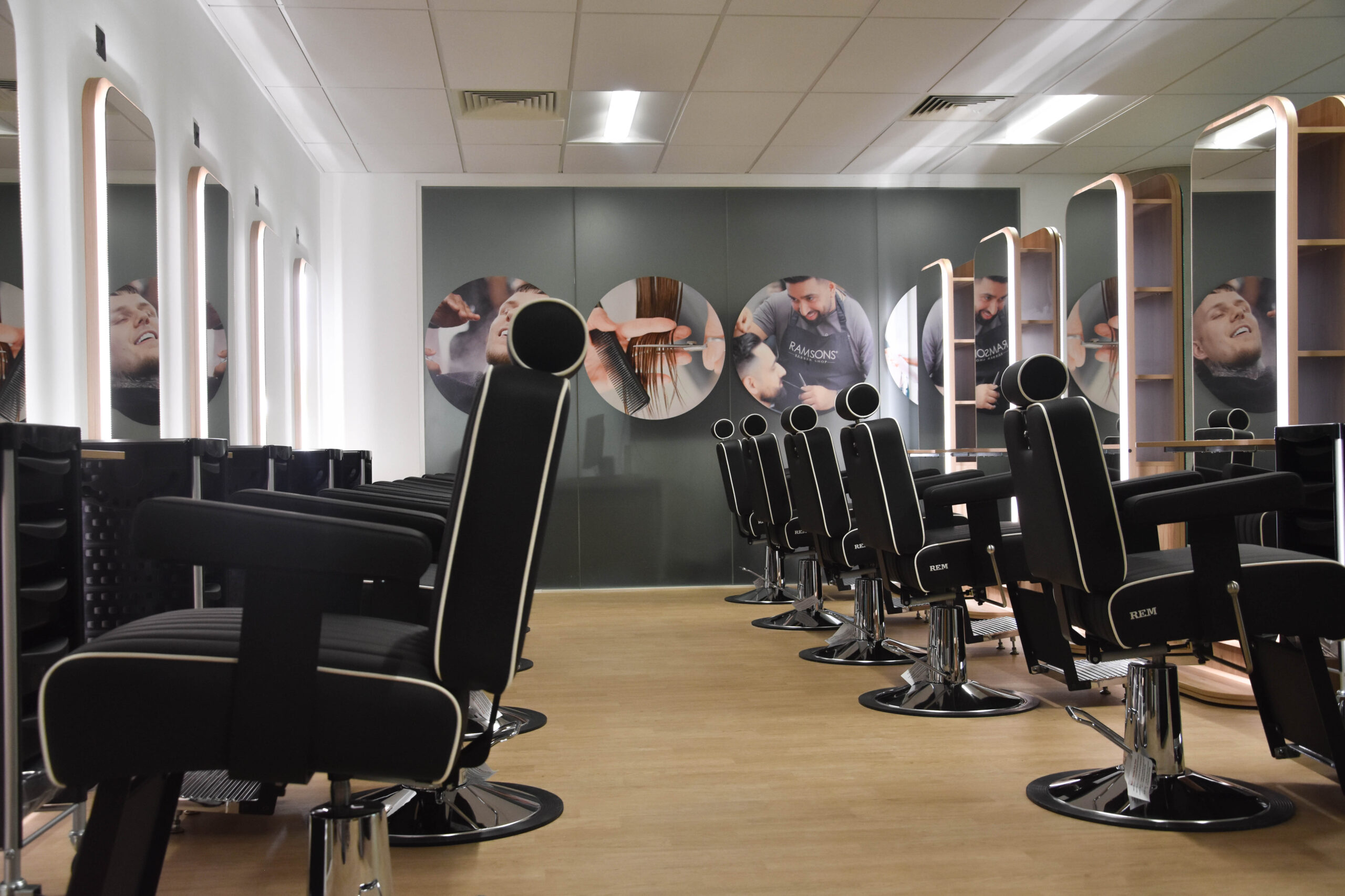 The new David Hockney Building barbering training salon. The room is well lit with features such as leather, swivel salon chairs and freestanding, light-up mirrors.