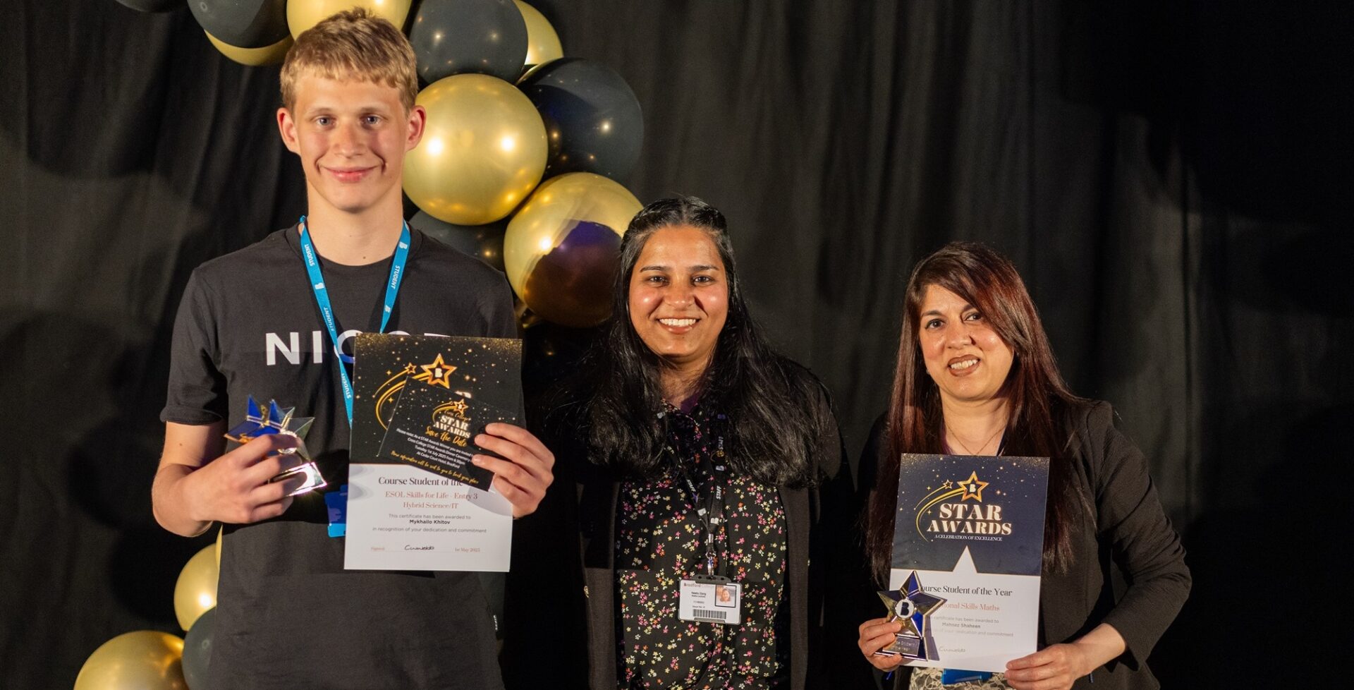 3 adult students standing with their awards in front of them