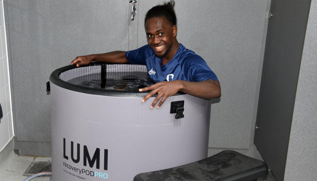 Male student wearing a blue T-Shirt sat in an Ice Bath smiling