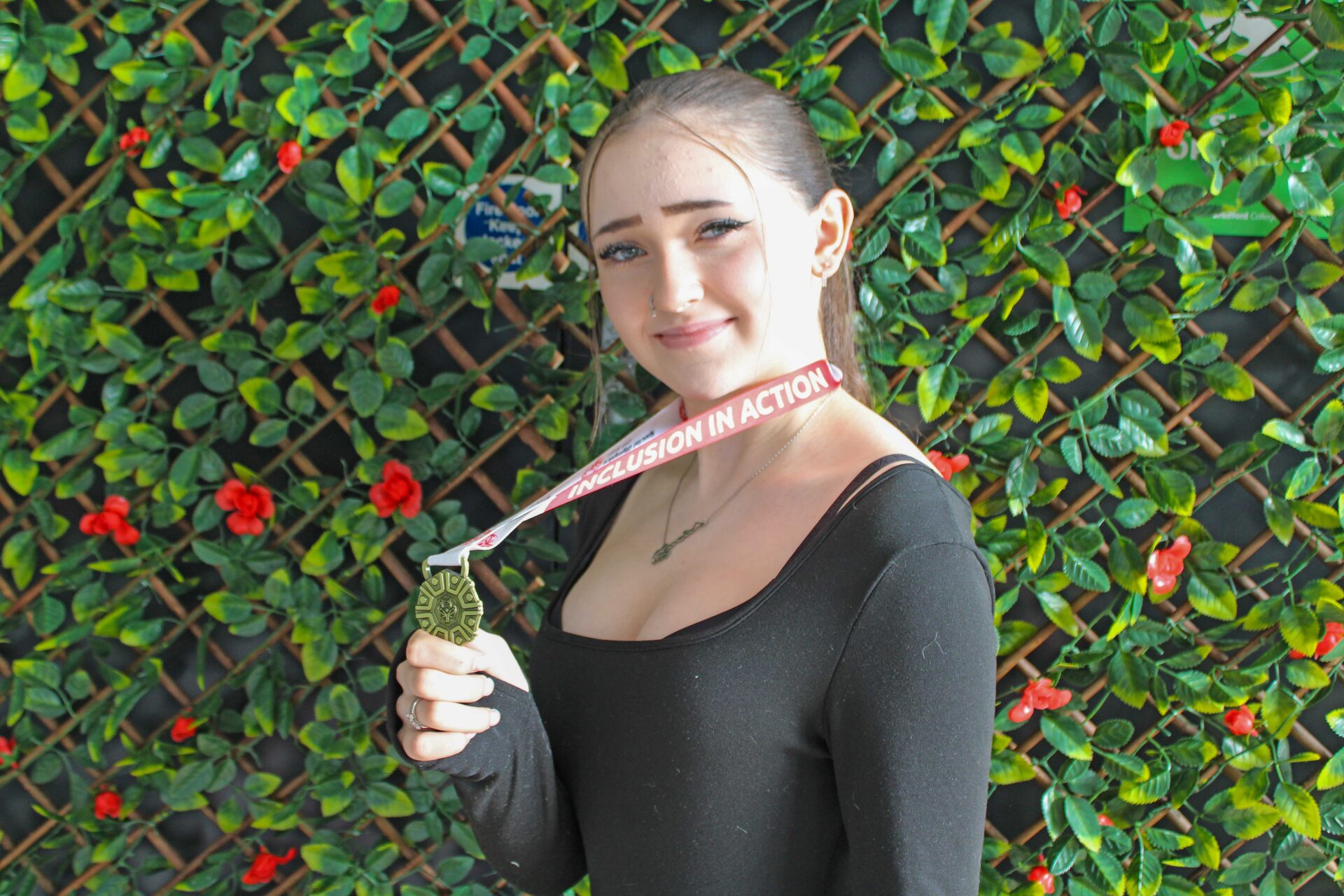 A young female holding a gold medal.