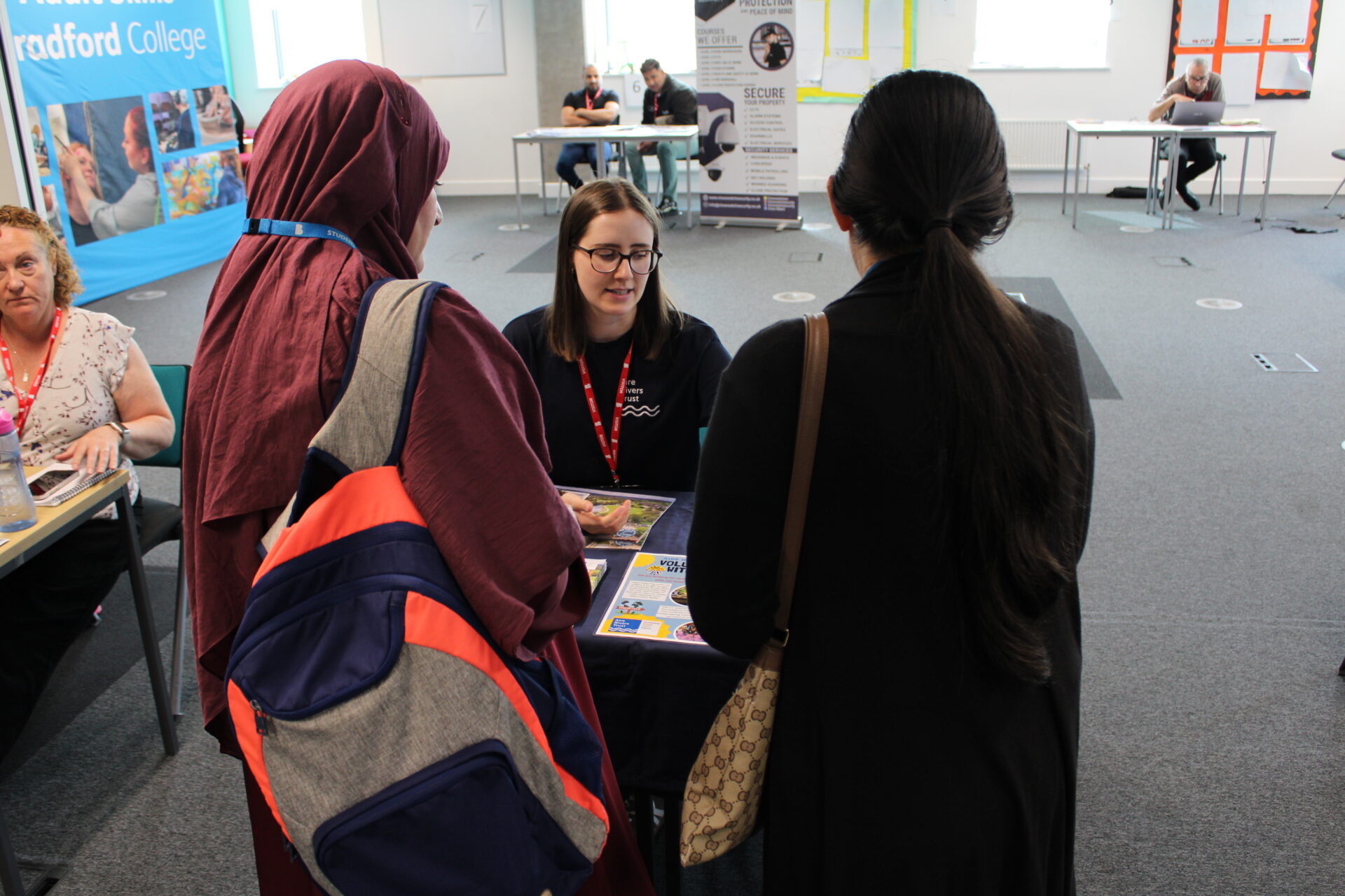 A group of people stand in front of a table and display talking together.