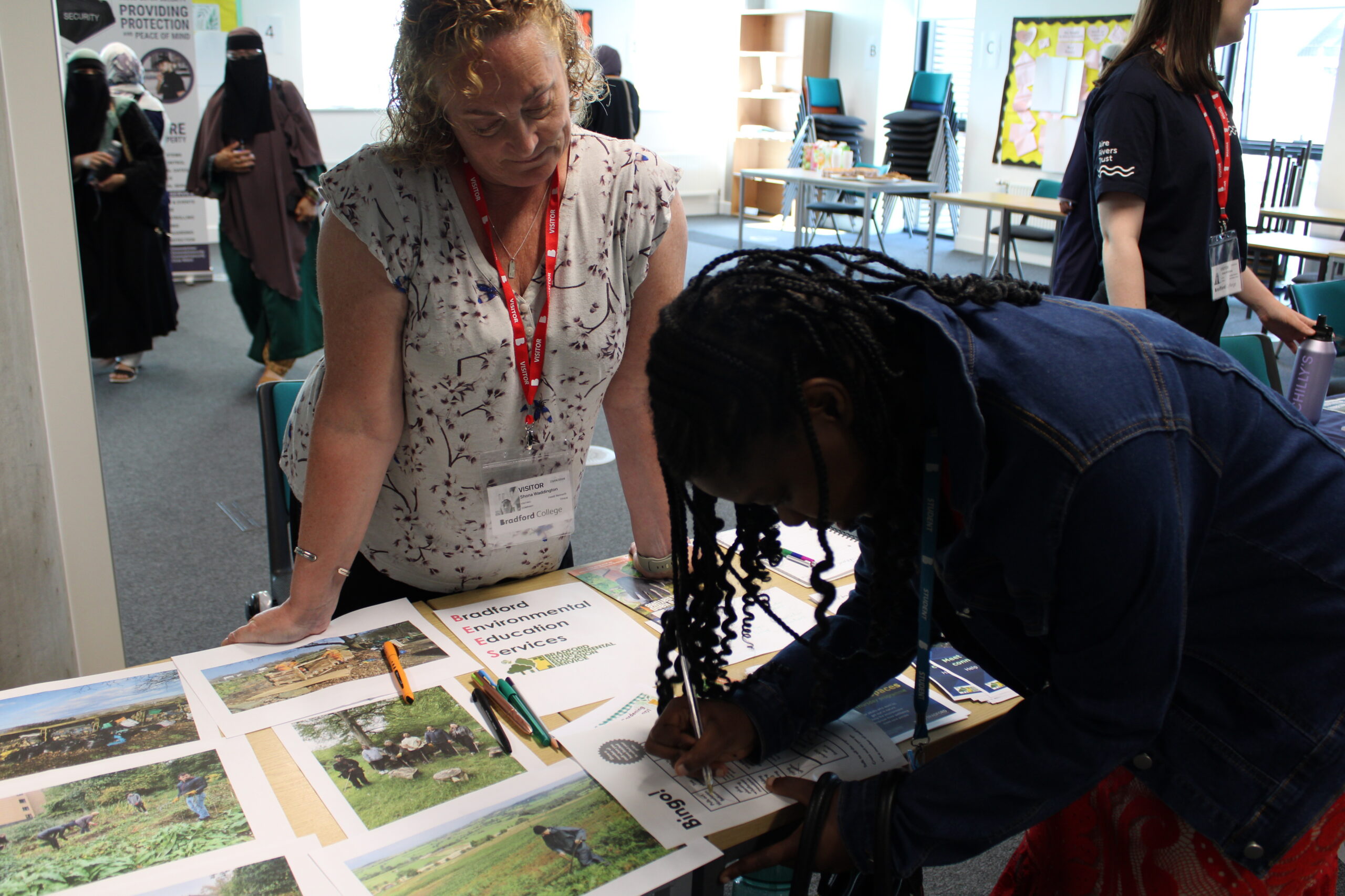 An adult learner and a visitor from Bradford Environmental Education Services talk about volunteering while filling in a leaflet.