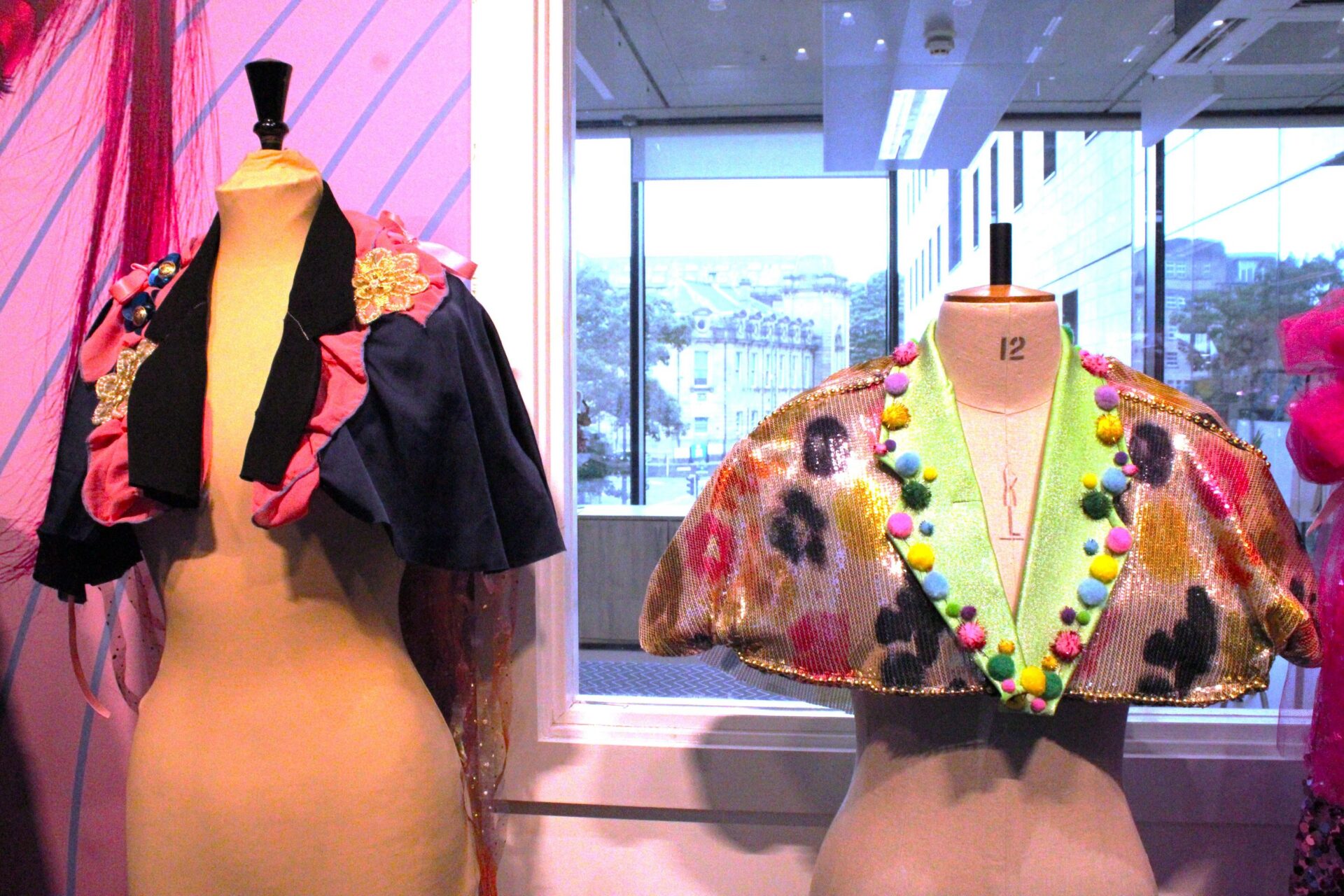 Two mannequin dummies stand side by side wearing colourful sparkly capes made by Bradford College fashion students.