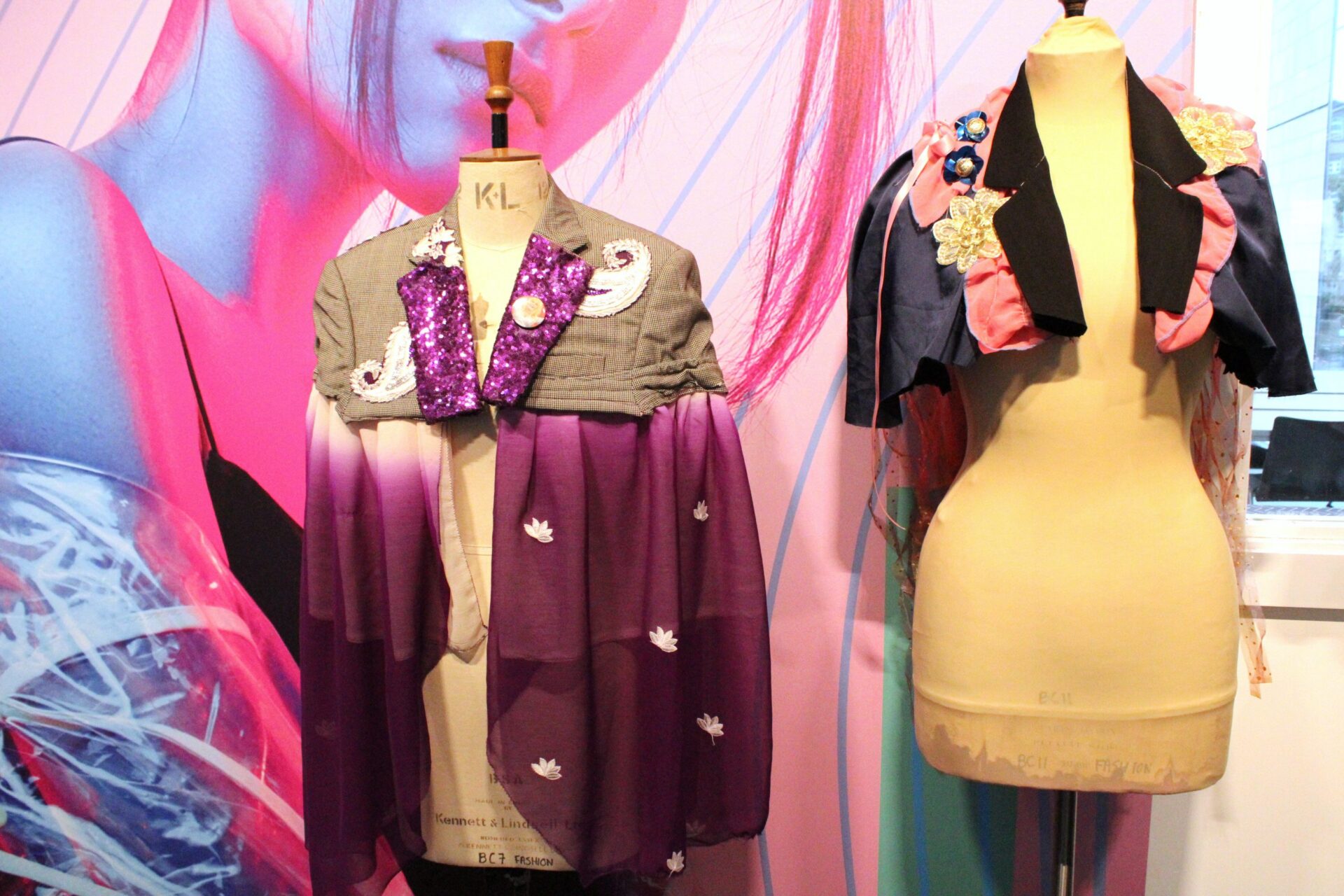 Two mannequin dummies stand side by side wearing colourful sparkly capes made by Bradford College fashion students.