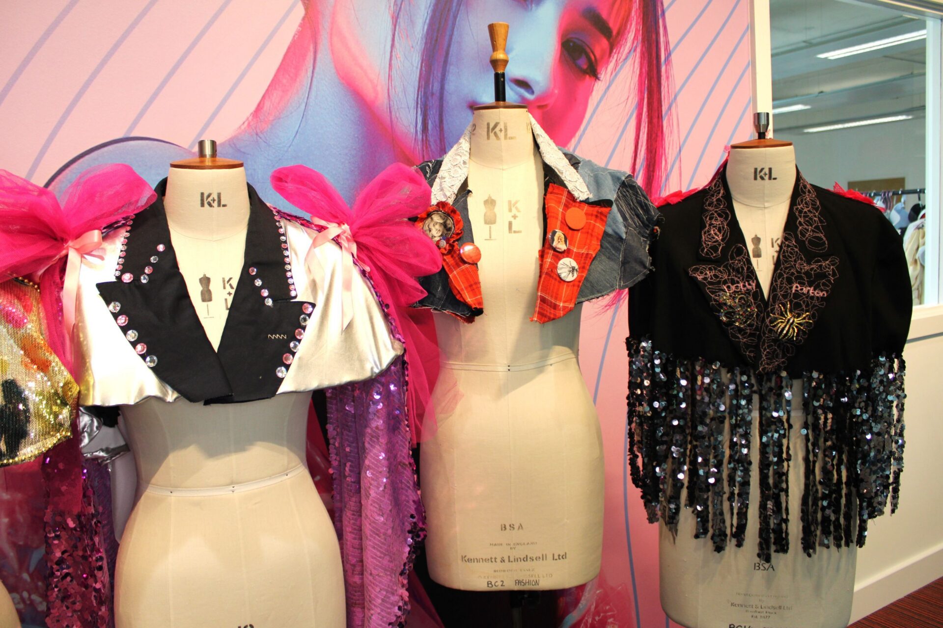 Three mannequin dummies stand in a row wearing colourful sparkly capes made by Bradford College fashion students.